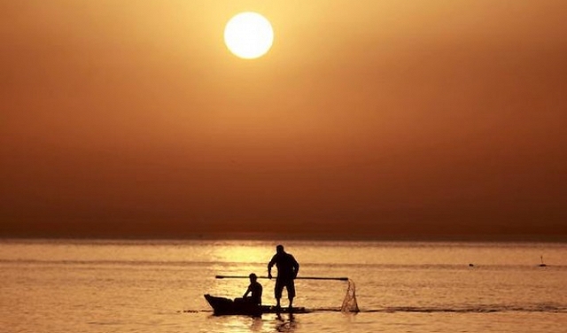 صورة تُظهر صياديْن فلسطينيّيْن في غزة، مع شروق الشمس،