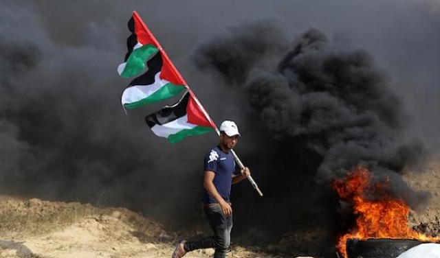 فلسطينيّ غزيّ يرفع الأعلام الفلسطينيّة 