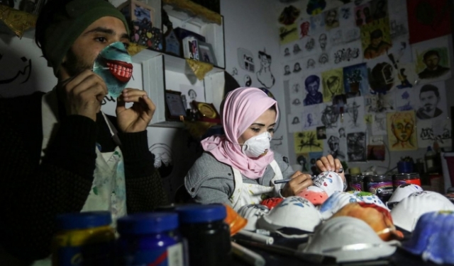 فلسطينيان يشجعان على استخدام الكمّامات الواقية من كورونا بتلوينها