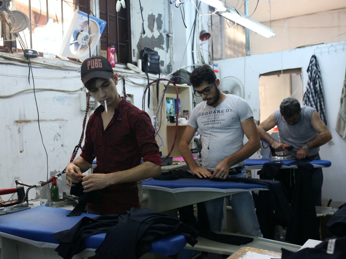 لاجئون سوريون يعملون في معمل للنسيج قبل الجائحة (رويترز)