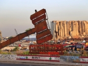 مجسّم ضخم مقابل آثار الدمار الذي خلفه انفجار مرفأ بيروت للمطالبة بالعدالة للضحايا
